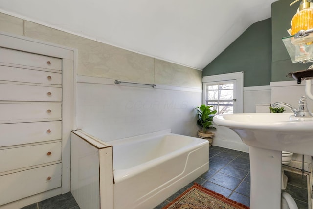 full bathroom with tile patterned floors, a tub, and lofted ceiling