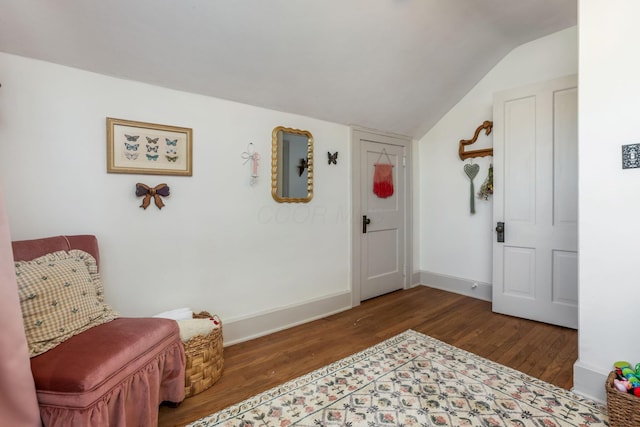 sitting room featuring lofted ceiling, baseboards, and wood finished floors