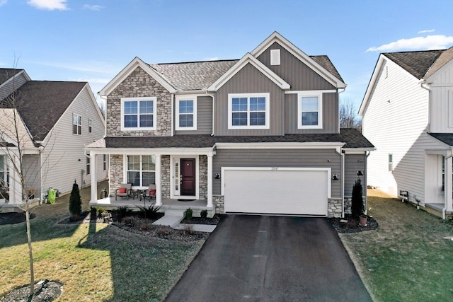 view of front of house with covered porch, a front lawn, and a garage