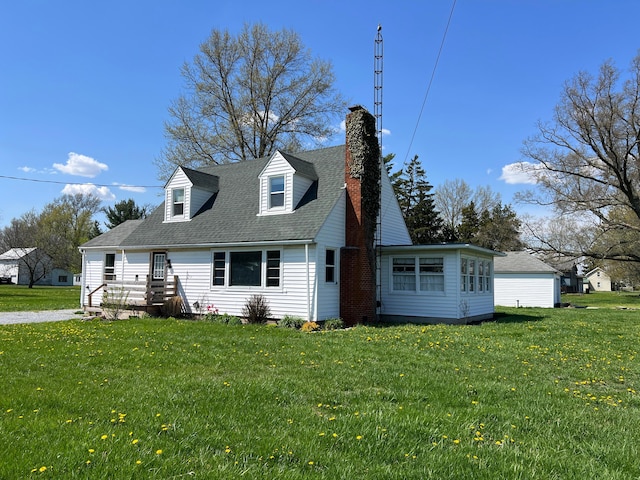 new england style home with a front yard, a shingled roof, and a chimney