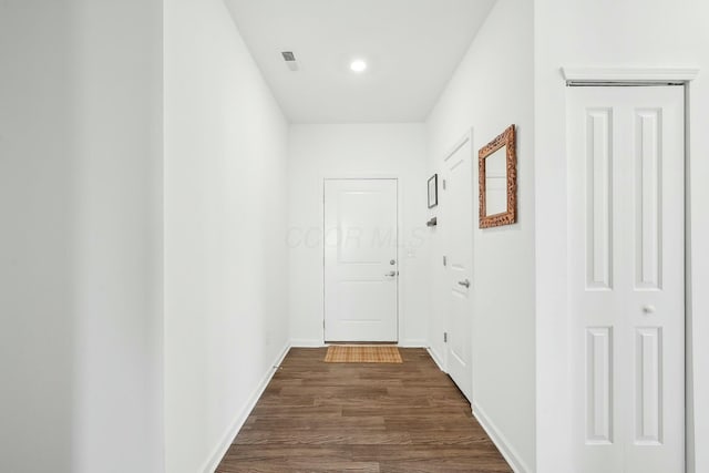 corridor with visible vents, dark wood finished floors, and baseboards