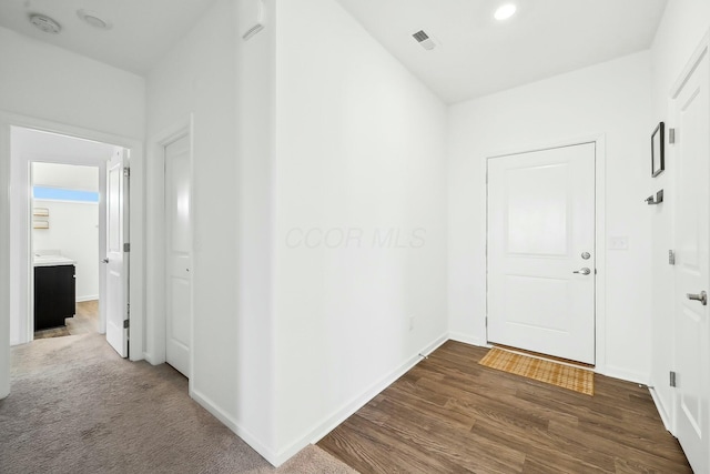 hall featuring visible vents, baseboards, and wood finished floors