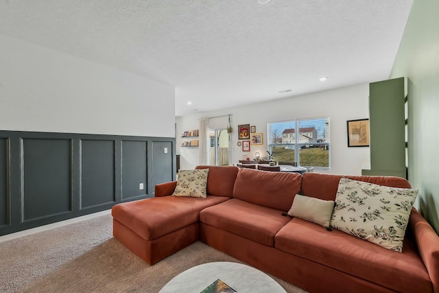 carpeted living area featuring a wainscoted wall, a decorative wall, a textured ceiling, and recessed lighting