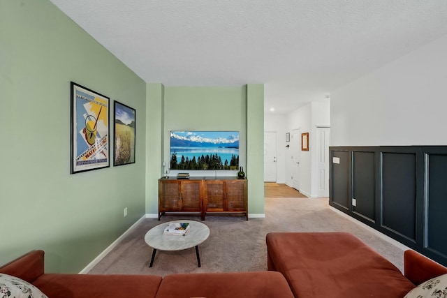 living area featuring light carpet, a textured ceiling, and baseboards