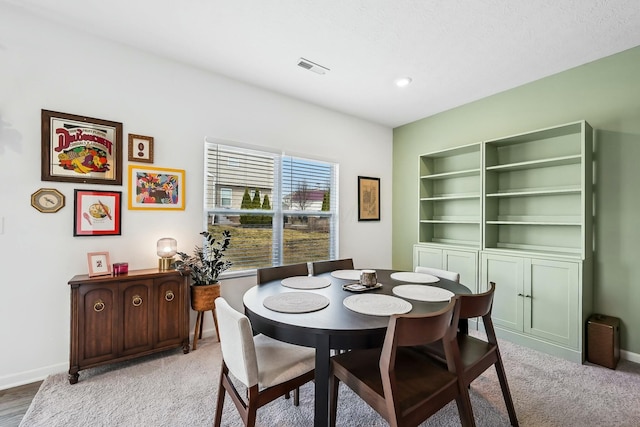 dining area with light colored carpet, visible vents, and baseboards