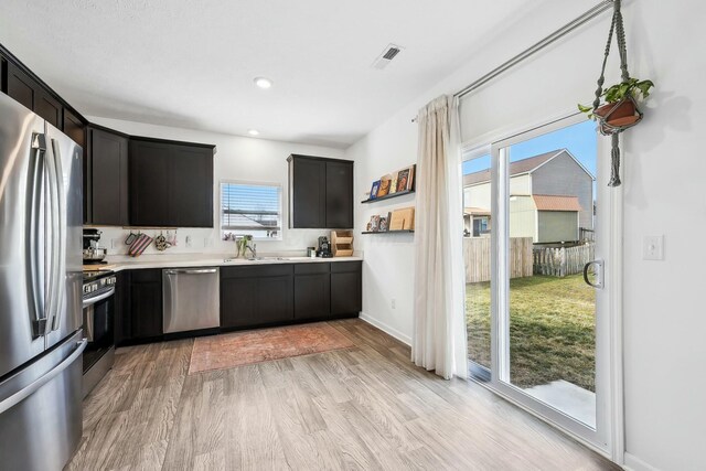 kitchen featuring light wood finished floors, visible vents, baseboards, appliances with stainless steel finishes, and light countertops