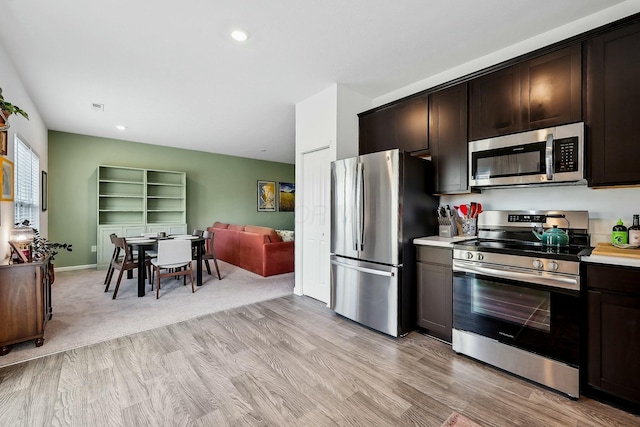 kitchen featuring dark brown cabinets, appliances with stainless steel finishes, light countertops, and light wood-style floors