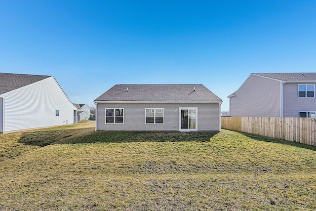 rear view of property with fence and a lawn