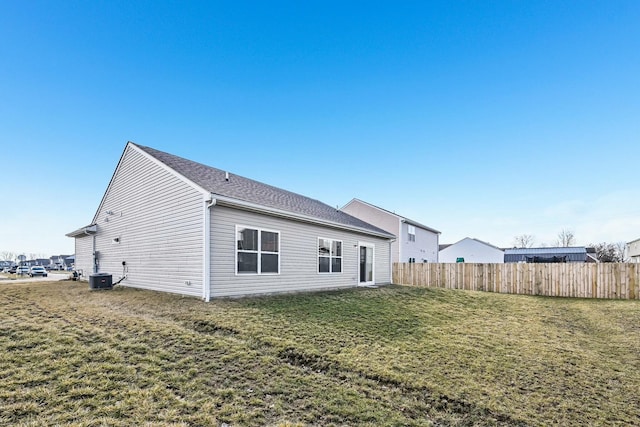 rear view of house featuring a shingled roof, fence, central AC, and a yard