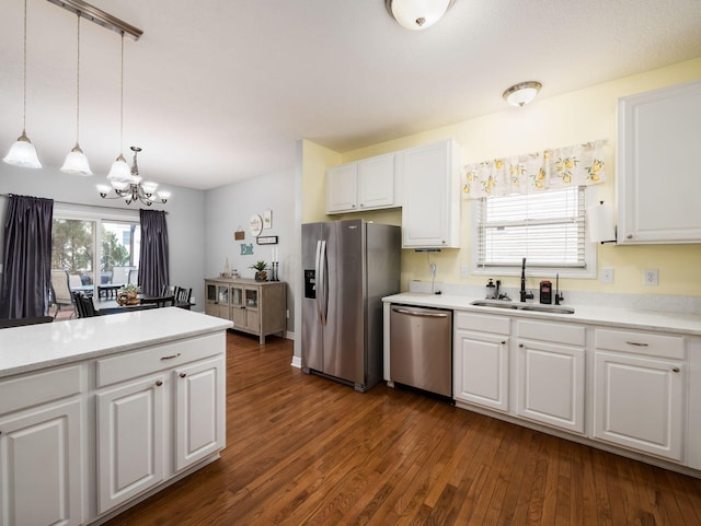 kitchen with sink, stainless steel appliances, dark hardwood / wood-style floors, white cabinets, and decorative light fixtures