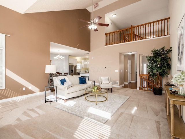 living area with baseboards, ceiling fan with notable chandelier, visible vents, and light colored carpet