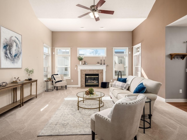 living area featuring light carpet, ceiling fan, baseboards, and a tile fireplace