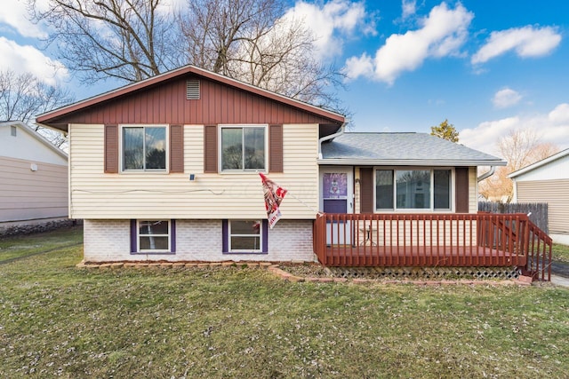 tri-level home with brick siding, a front yard, and a wooden deck