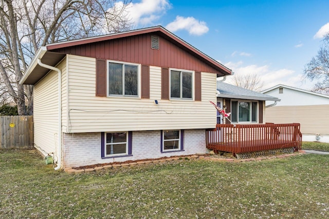 tri-level home featuring a front lawn, fence, and a wooden deck