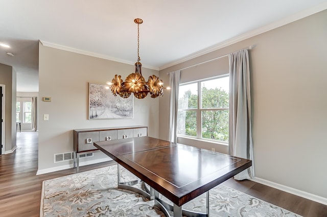 dining space with hardwood / wood-style flooring, ornamental molding, and a notable chandelier