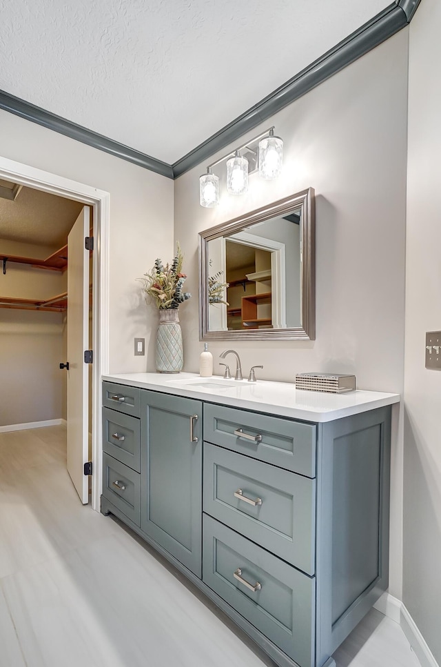 bathroom featuring vanity, crown molding, and a textured ceiling