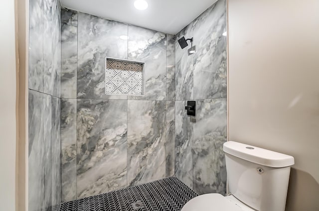 bathroom featuring tiled shower and toilet