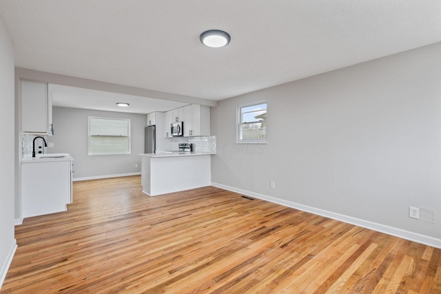 unfurnished living room featuring sink and light hardwood / wood-style flooring