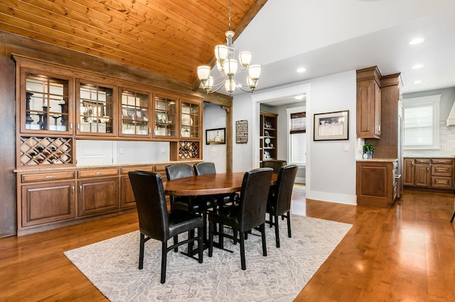 dining space featuring a notable chandelier, wood finished floors, recessed lighting, baseboards, and vaulted ceiling