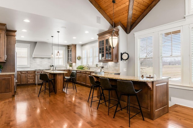 kitchen featuring premium range hood, a kitchen island, stainless steel appliances, a breakfast bar area, and vaulted ceiling