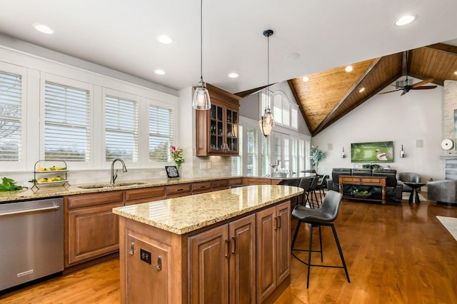 kitchen with light wood-style flooring, a sink, open floor plan, brown cabinetry, and dishwasher