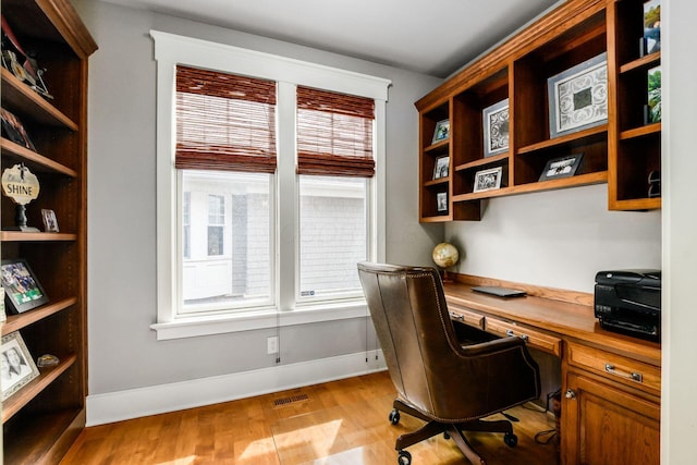 office with visible vents, plenty of natural light, light wood-style flooring, and built in desk