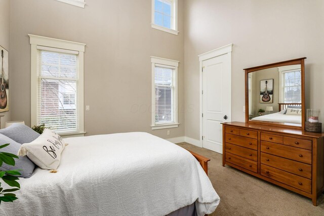 bedroom featuring baseboards, a towering ceiling, and carpet floors