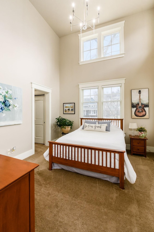 carpeted bedroom featuring baseboards, an inviting chandelier, and a towering ceiling