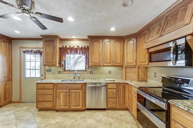 kitchen featuring light stone counters, stainless steel appliances, sink, and a textured ceiling