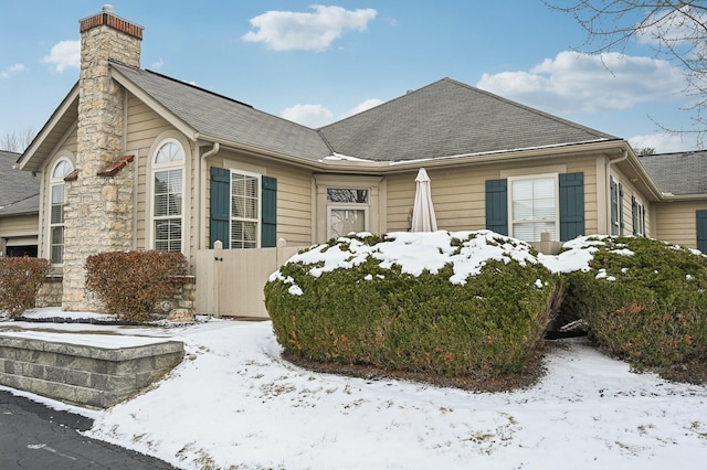 single story home featuring a shingled roof and a chimney