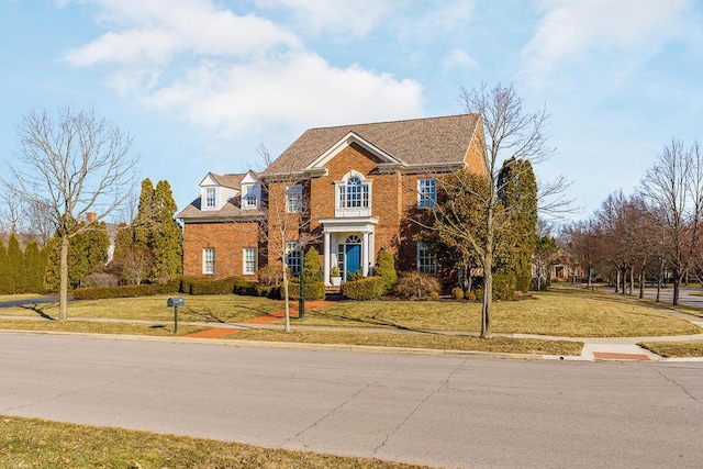 colonial home with brick siding and a front yard