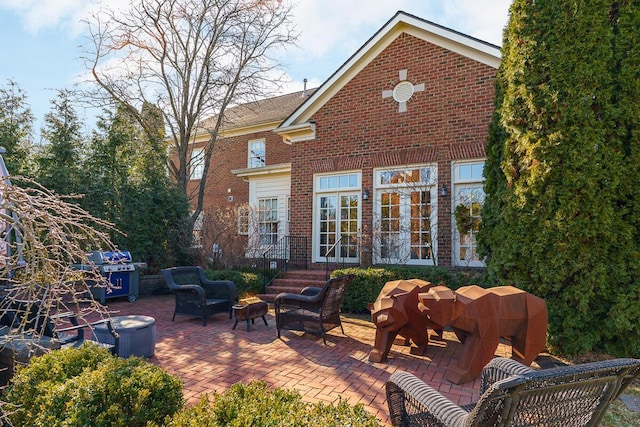 back of property with a patio area, brick siding, and a fire pit