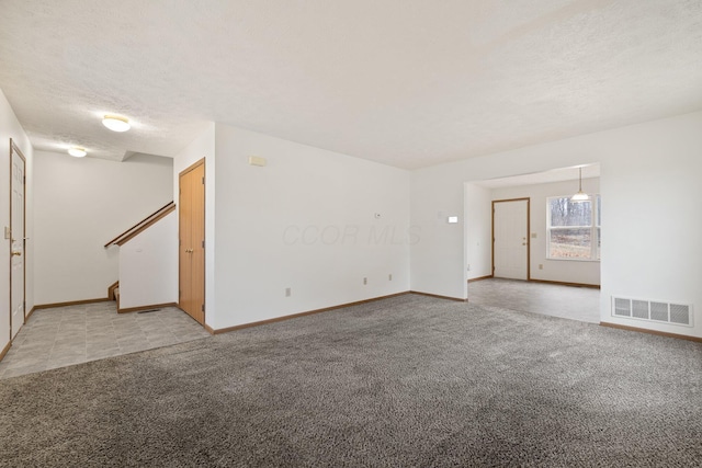 unfurnished living room with light carpet and a textured ceiling