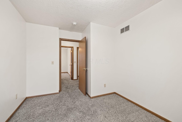 empty room with carpet floors and a textured ceiling