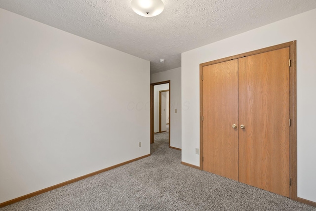 unfurnished bedroom featuring light colored carpet, a textured ceiling, and a closet