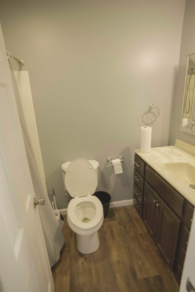 bathroom featuring toilet, vanity, baseboards, and wood finished floors