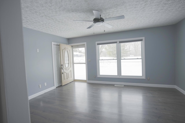 unfurnished room featuring visible vents, a textured ceiling, baseboards, ceiling fan, and dark wood-style flooring