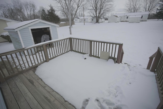 snow covered deck featuring an outdoor structure and a shed