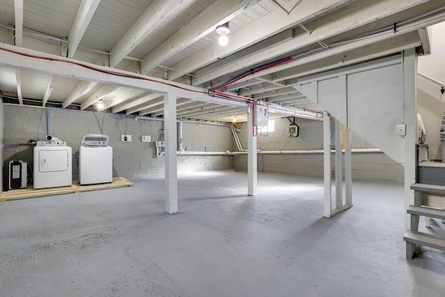 basement featuring electric panel and washing machine and clothes dryer