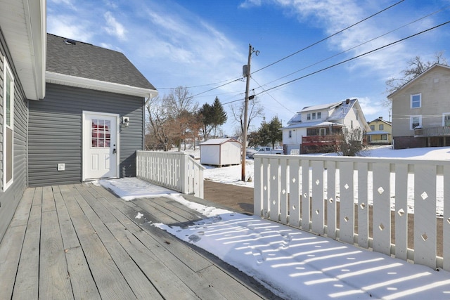 snow covered deck featuring a shed