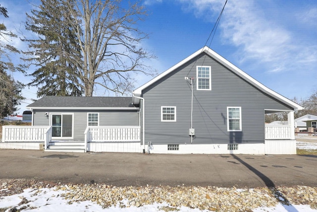 snow covered back of property with covered porch