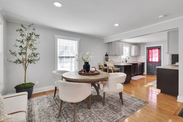 dining room with ornamental molding, sink, and light wood-type flooring