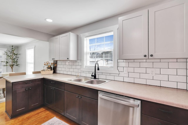 kitchen with white cabinetry, kitchen peninsula, plenty of natural light, sink, and stainless steel dishwasher