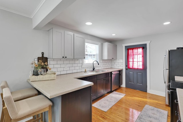 kitchen with light hardwood / wood-style flooring, tasteful backsplash, a breakfast bar area, dishwasher, and sink