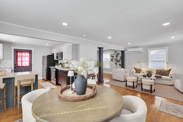 dining area with ornamental molding, light hardwood / wood-style flooring, a wall unit AC, and a wealth of natural light