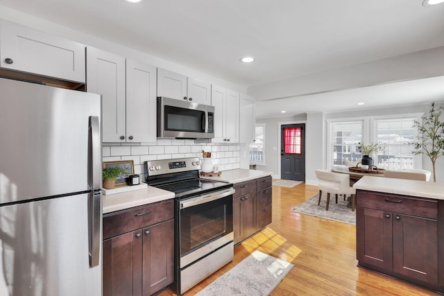 kitchen featuring decorative backsplash, stainless steel appliances, light hardwood / wood-style floors, and dark brown cabinetry