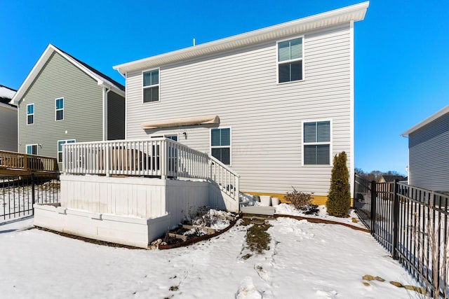 snow covered back of property with a deck