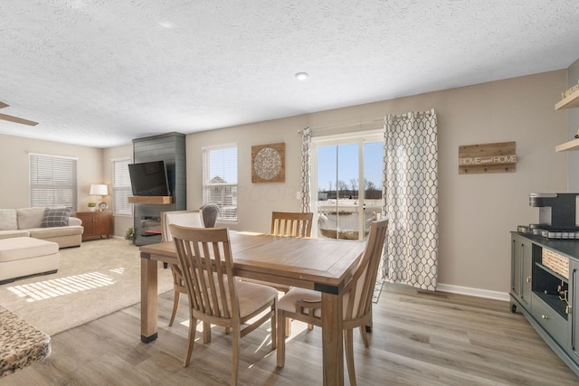 dining room with light wood-type flooring and a textured ceiling