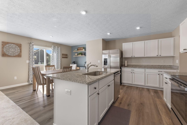 kitchen featuring a kitchen island with sink, sink, appliances with stainless steel finishes, white cabinets, and dark hardwood / wood-style floors