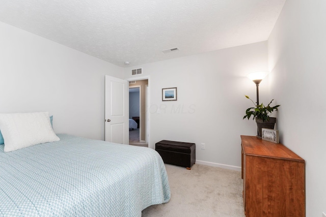 bedroom featuring a textured ceiling and light colored carpet